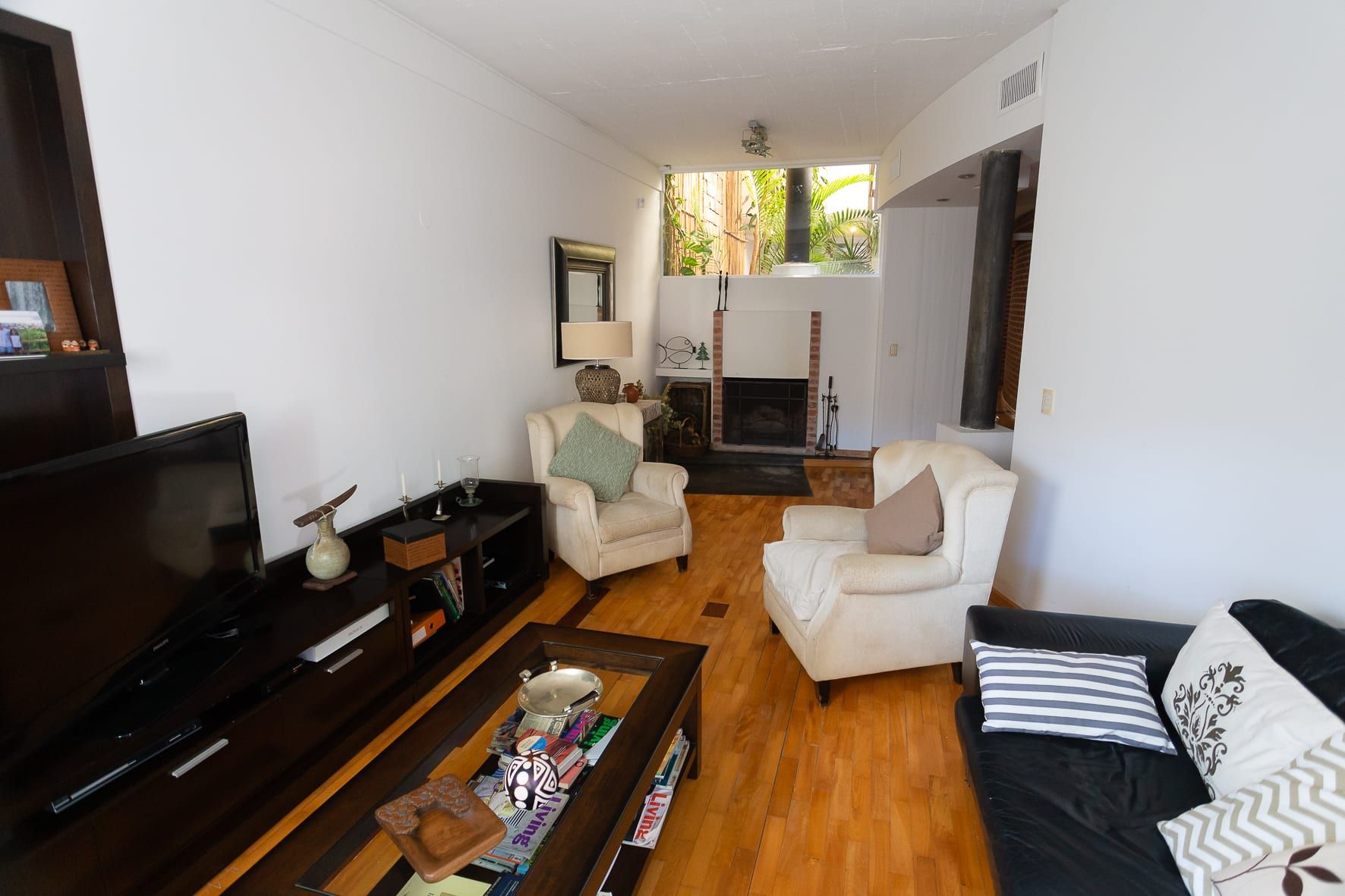Living con hogar a leña, pisos de madera y sillones frente al patio interno de la casa Chiclana