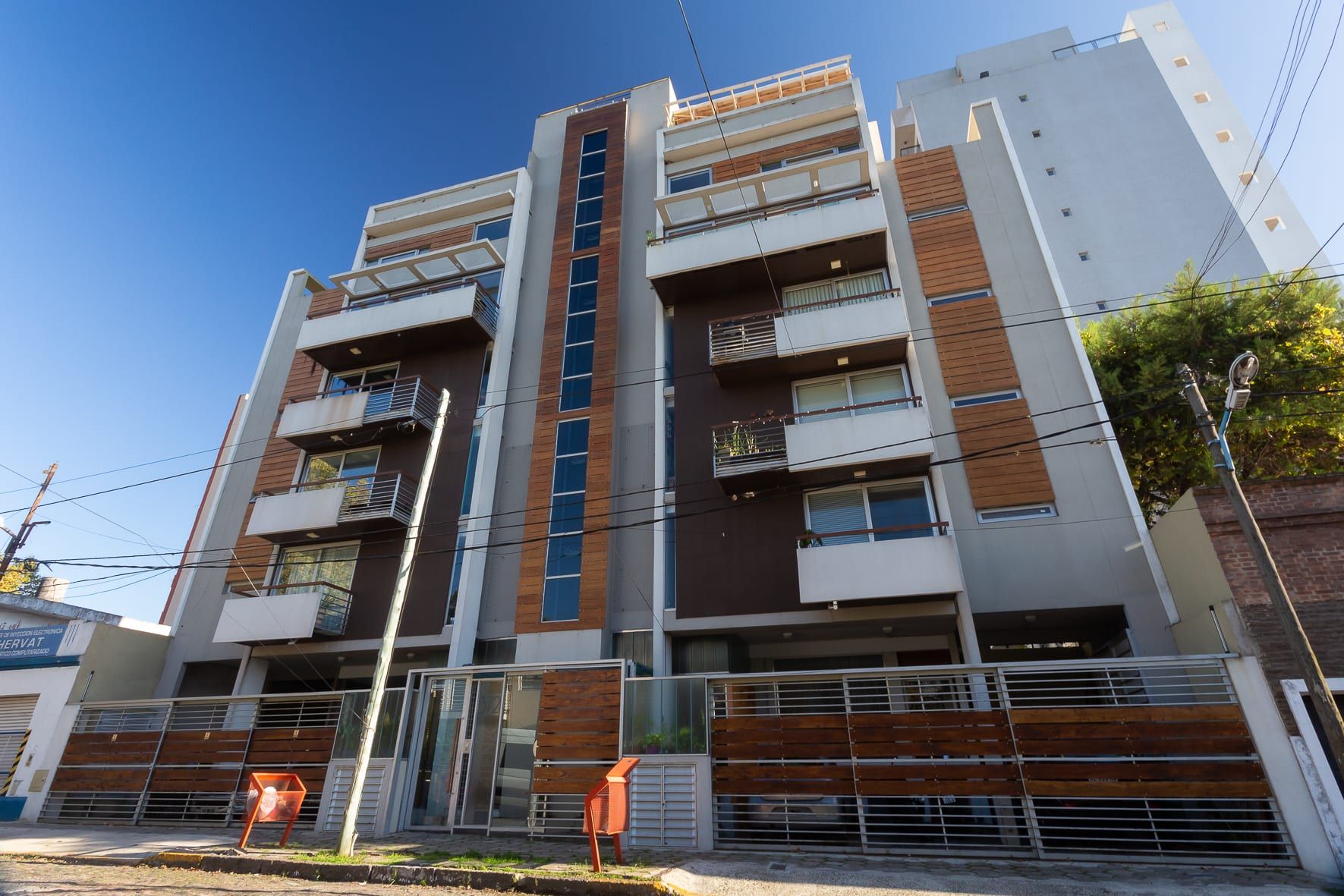 Fachada de Matienzo 372 desde la calle: balcones, revestimiento de madera y rejas de acceso vehicular
