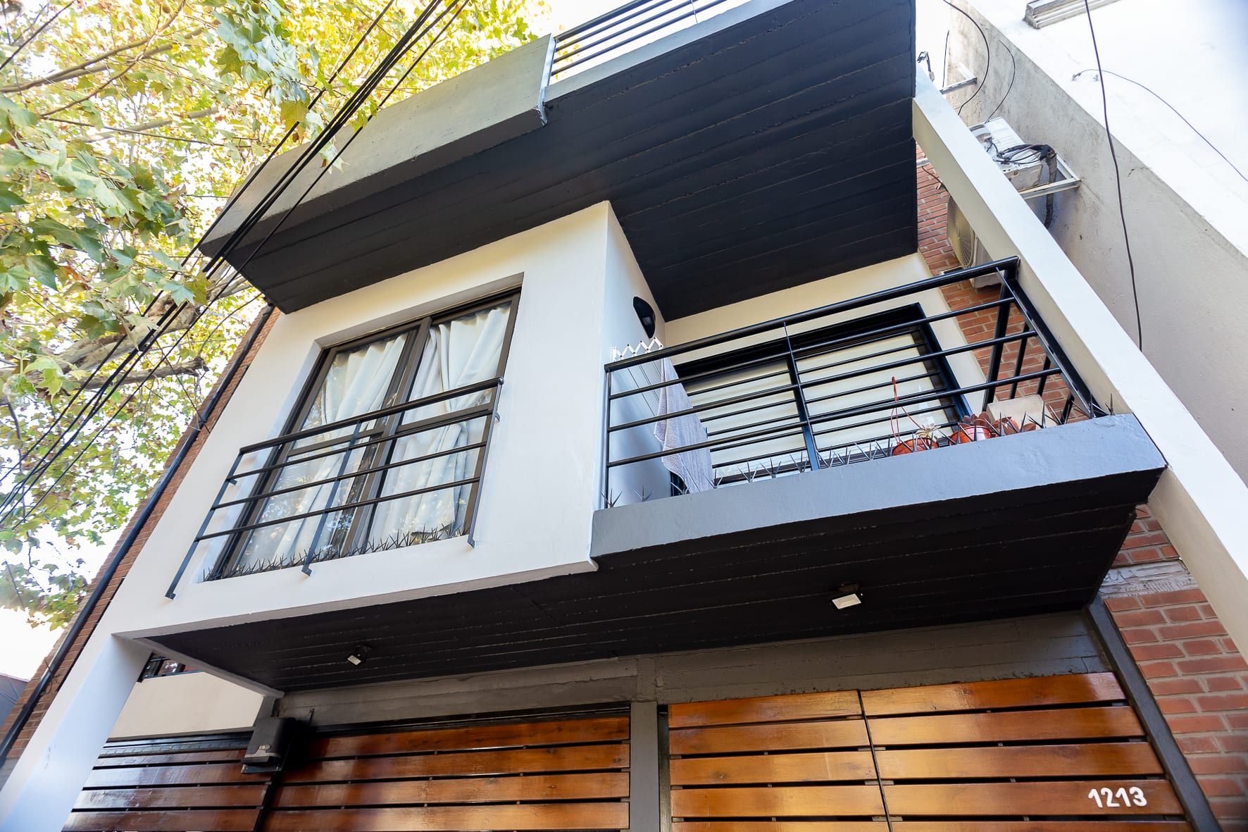 Fachada de Lavalle 1213 en contrapicado: balcones con barandas negras, hormigón pintado y ladrillo visto