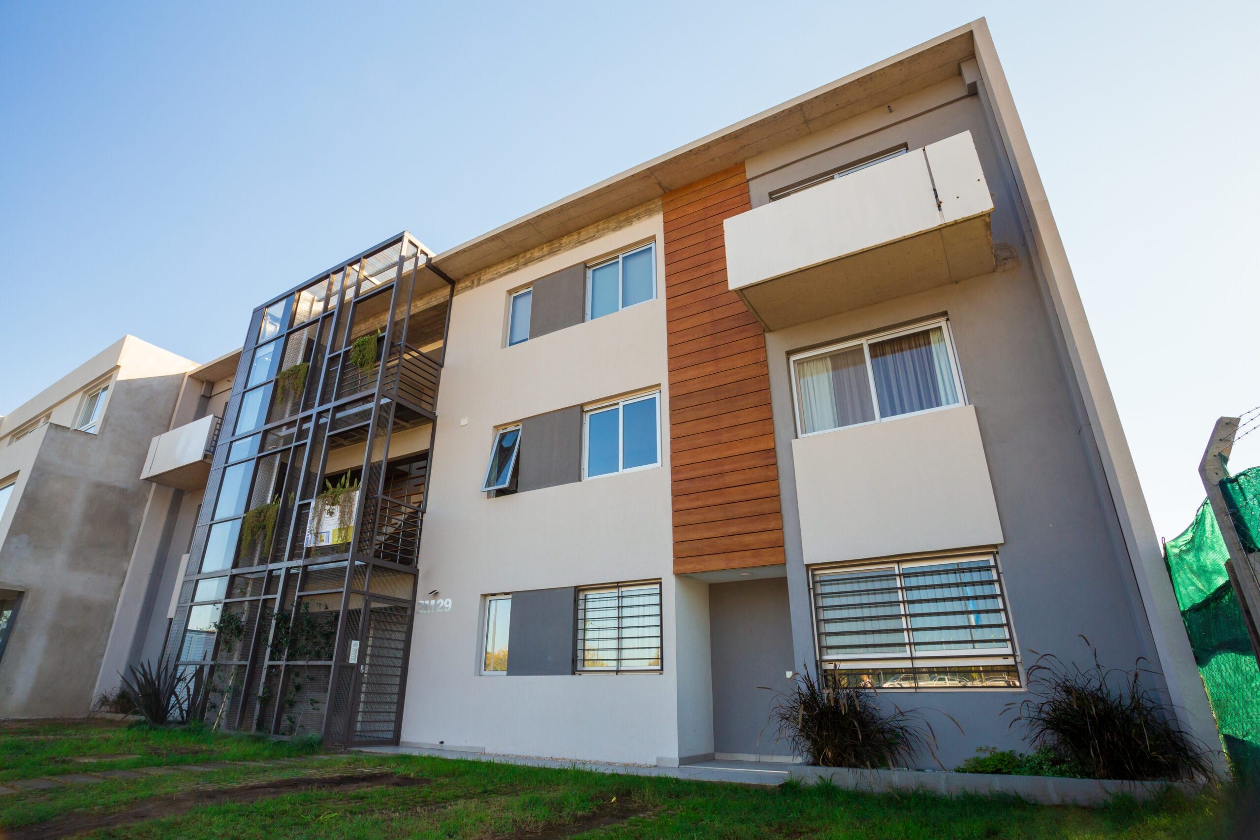 Fachada terminada del edificio Nuevo Quilmes 2M29: tres niveles con revestimiento de madera, balcones y caja de escalera metálica