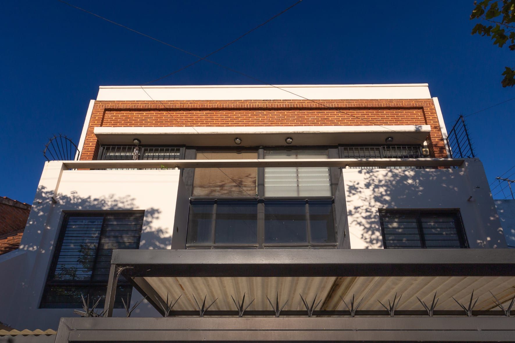 Fachada de Rawson 140 en contrapicado: banda de ladrillo visto sobre balcones blancos y carpinterías negras