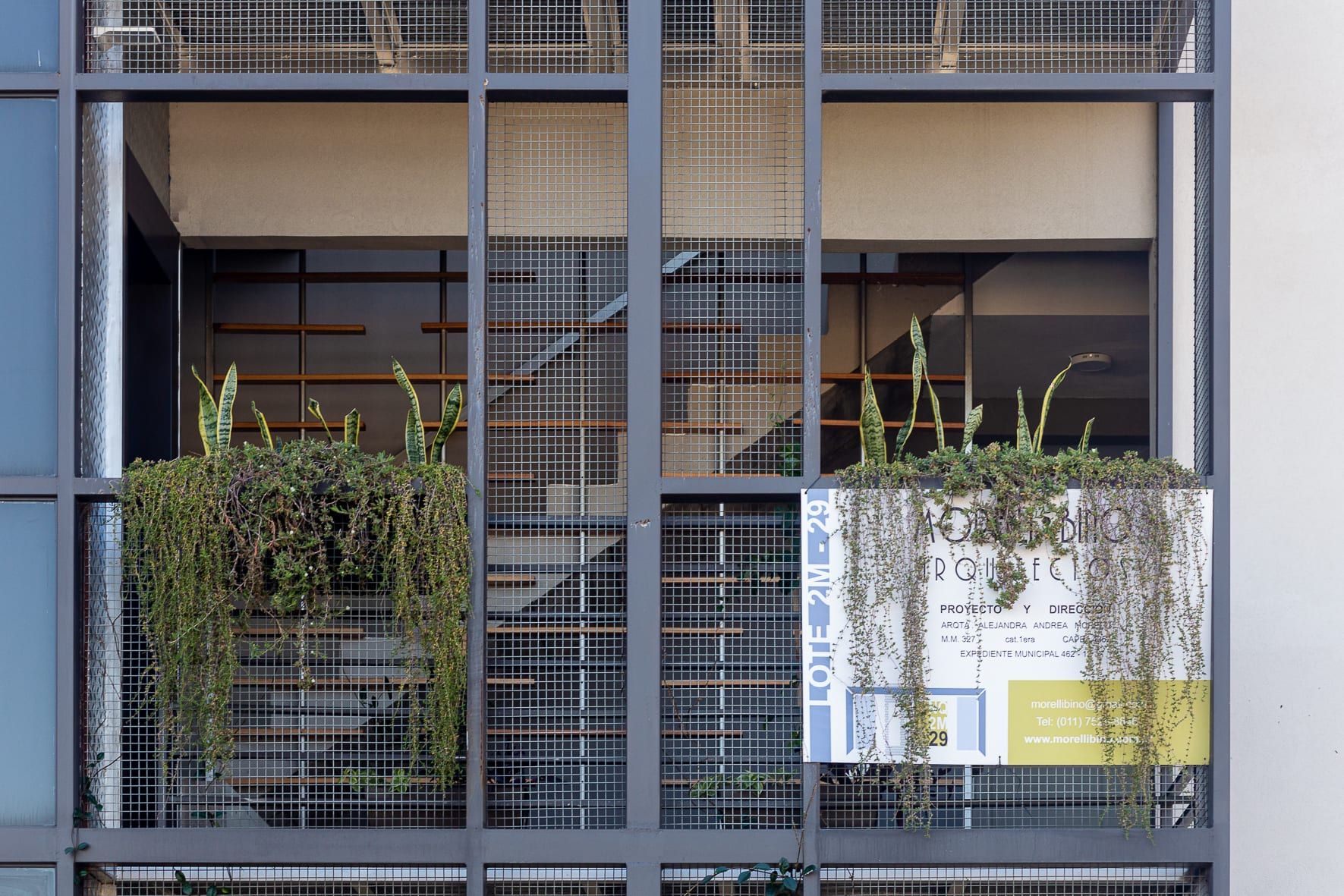 Detalle de la caja de escalera con parasoles metálicos, jardineras colgantes y cartel de obra de MORELLIBINO en el lote 2M-29