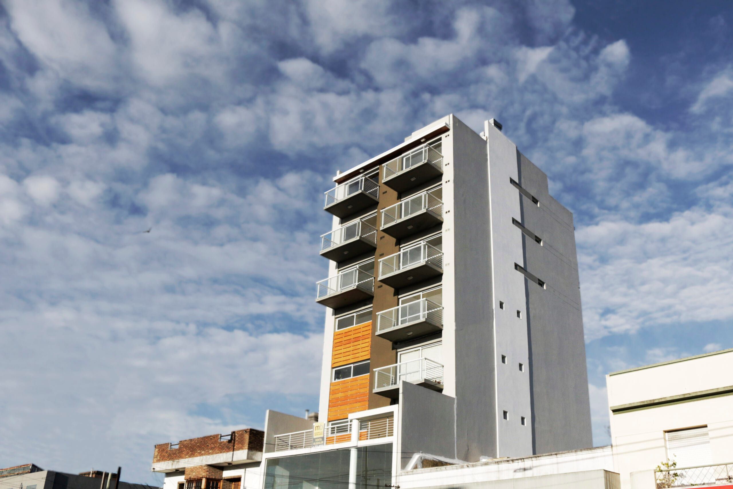 Edificio Yrigoyen 37 terminado visto desde la calle: torre de siete pisos con balcones y frente de listones naranjas
