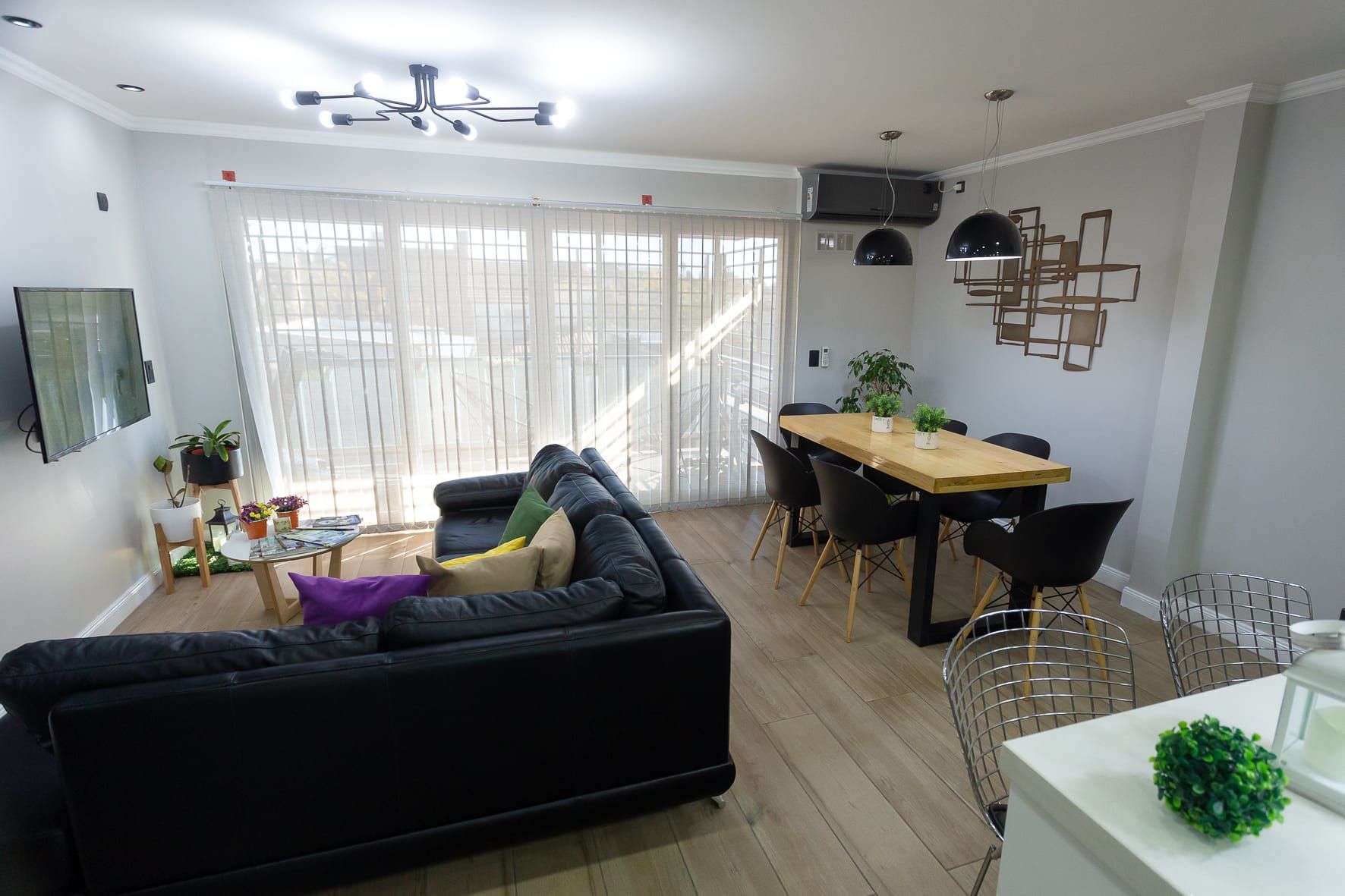 Living comedor luminoso con piso símil madera, sillón esquinero y mesa con vista al balcón