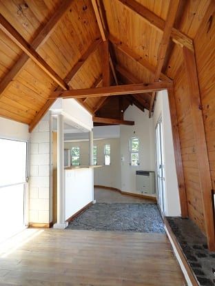 Interior de unidad en San Luis: techo a dos aguas de madera, paso al estar-cocina y piso de entrada en piedra