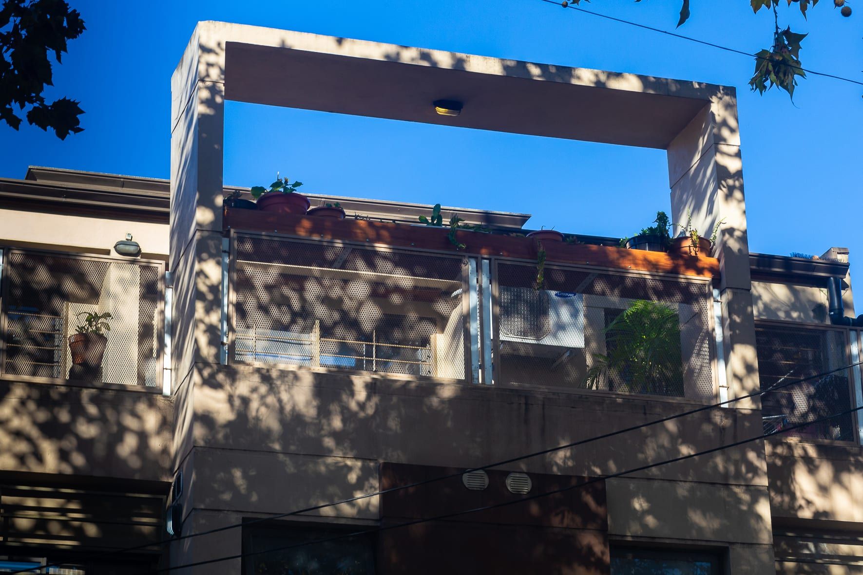 Detalle de la terraza y balcones de Formosa 10 al atardecer, con pérgola de hormigón, barandas metálicas y macetas