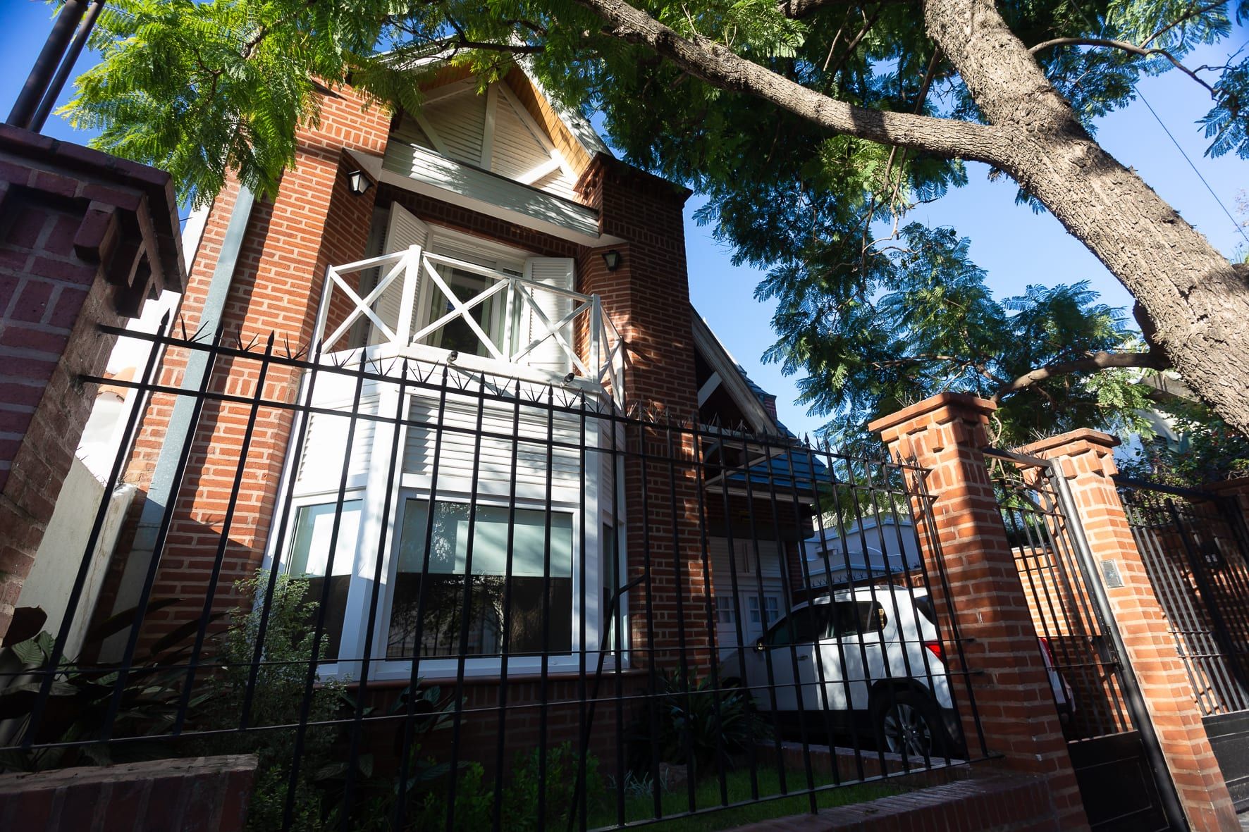 Fachada de ladrillo visto de la casa Chiclana desde la calle, con balcón blanco y reja negra